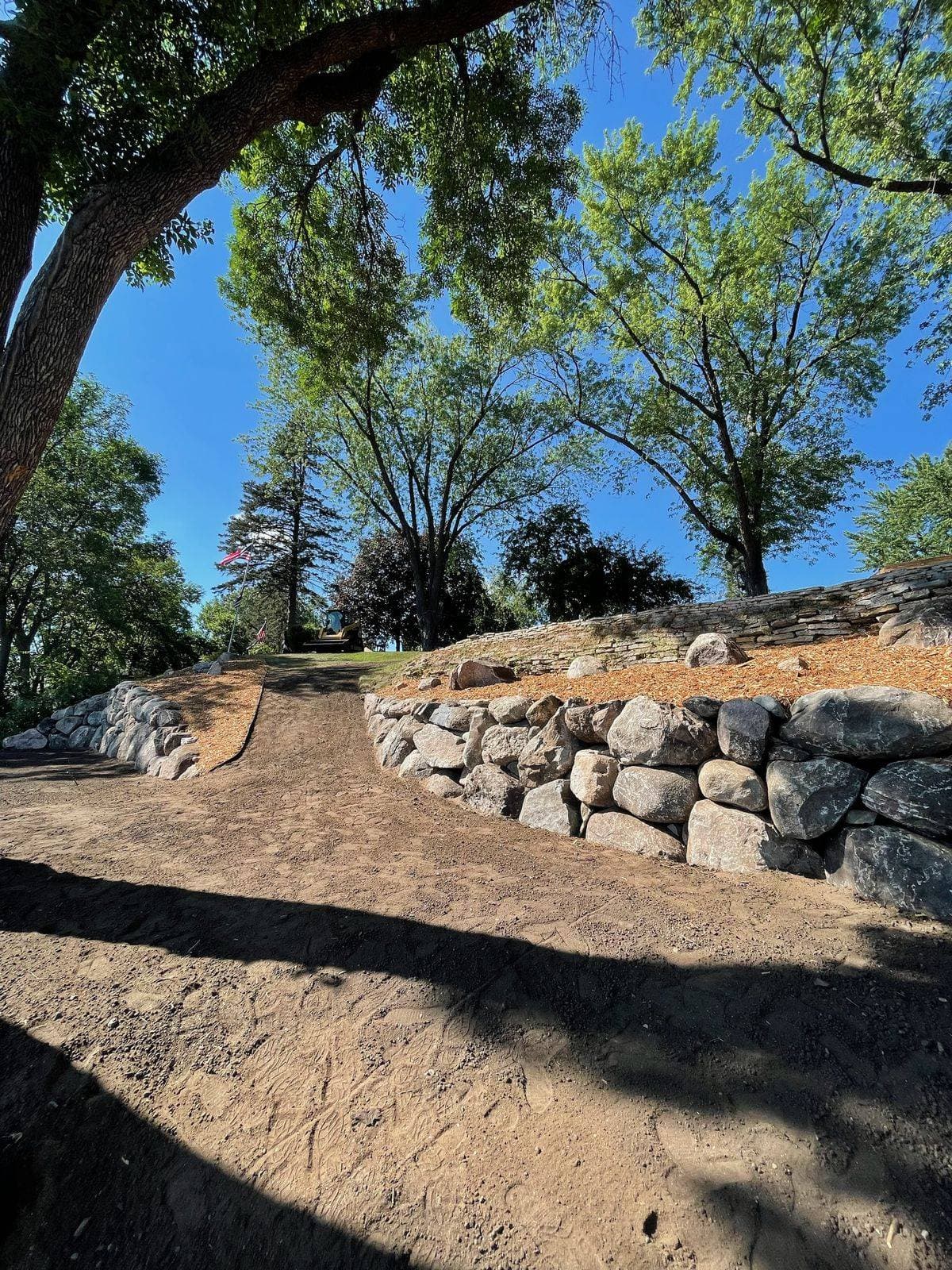 Fieldstone boulder wall stabilizing a regraded shoreline bank with fresh mulch above